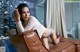 A woman sitting on top of a brown couch next to a pool.