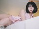 A woman in a pink dress sitting on a white couch.