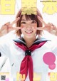 A woman in a sailor outfit making a peace sign with her hands.