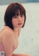 A woman in a pink bikini sitting on the edge of a pool.