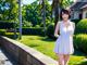 A woman in a white dress standing on a sidewalk.