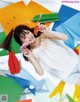 A woman laying on the ground surrounded by colorful paper airplanes.