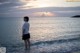 A woman standing in the ocean at sunset. 