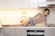 A woman laying on a kitchen counter next to a sink.